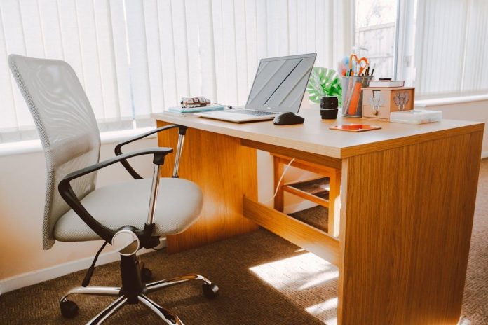 Ergonomic office chair next to a wooden desk in a sunlit office