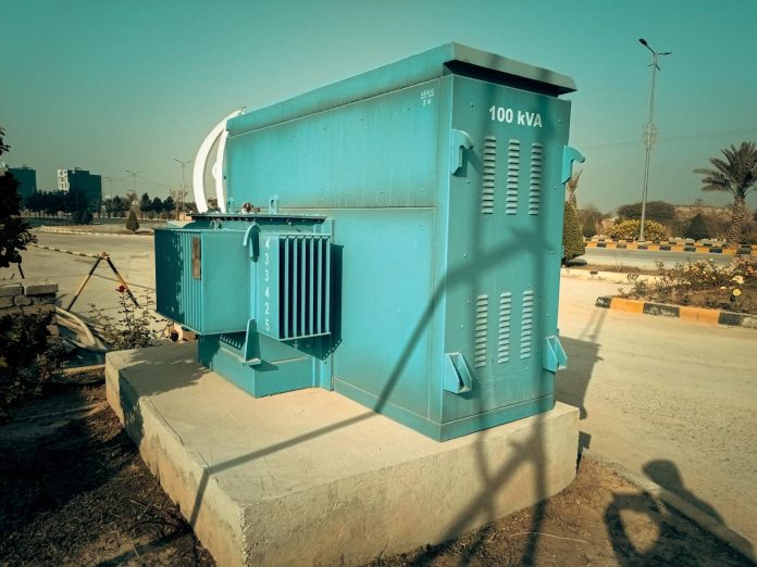 Blue standby diesel generator on concrete platform in daylight.