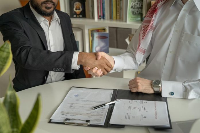 Businessmen shaking hands over financial documents