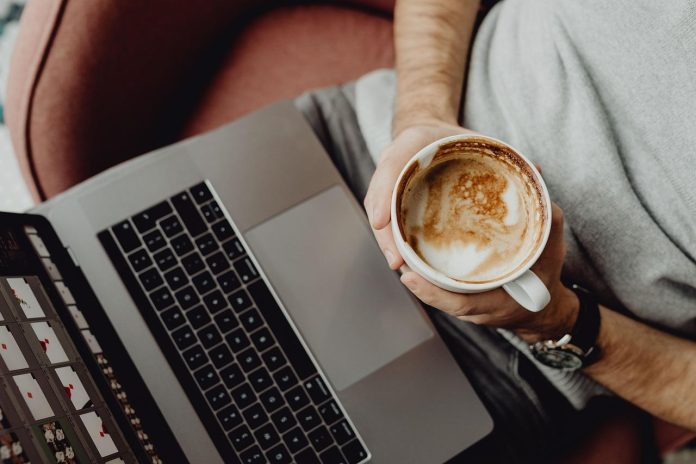 Man analyzing data on laptop while holding coffee cup.