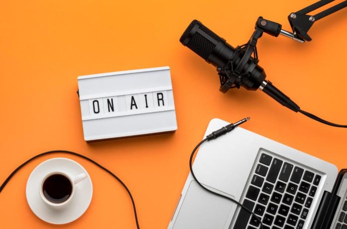 Podcast recording setup with microphone, laptop, coffee, and 