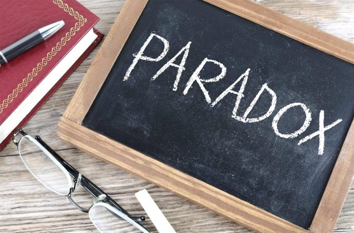 Chalkboard showing the word “Paradox” with notebook and glasses