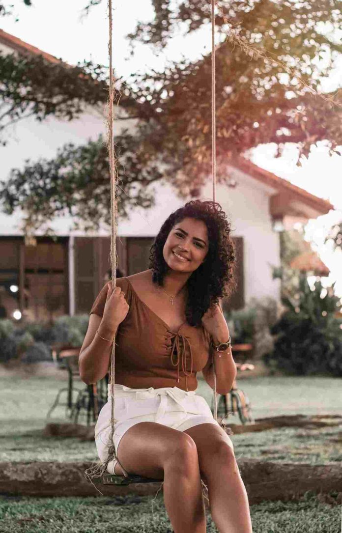 Woman relaxing on backyard swing in sunny yard