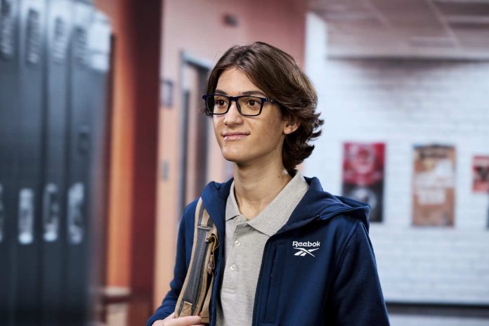 Student standing in a school hallway with lockers