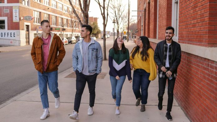 Group of teenagers walking together on a city street, laughing and enjoying a carefree moment while facing future life decisions